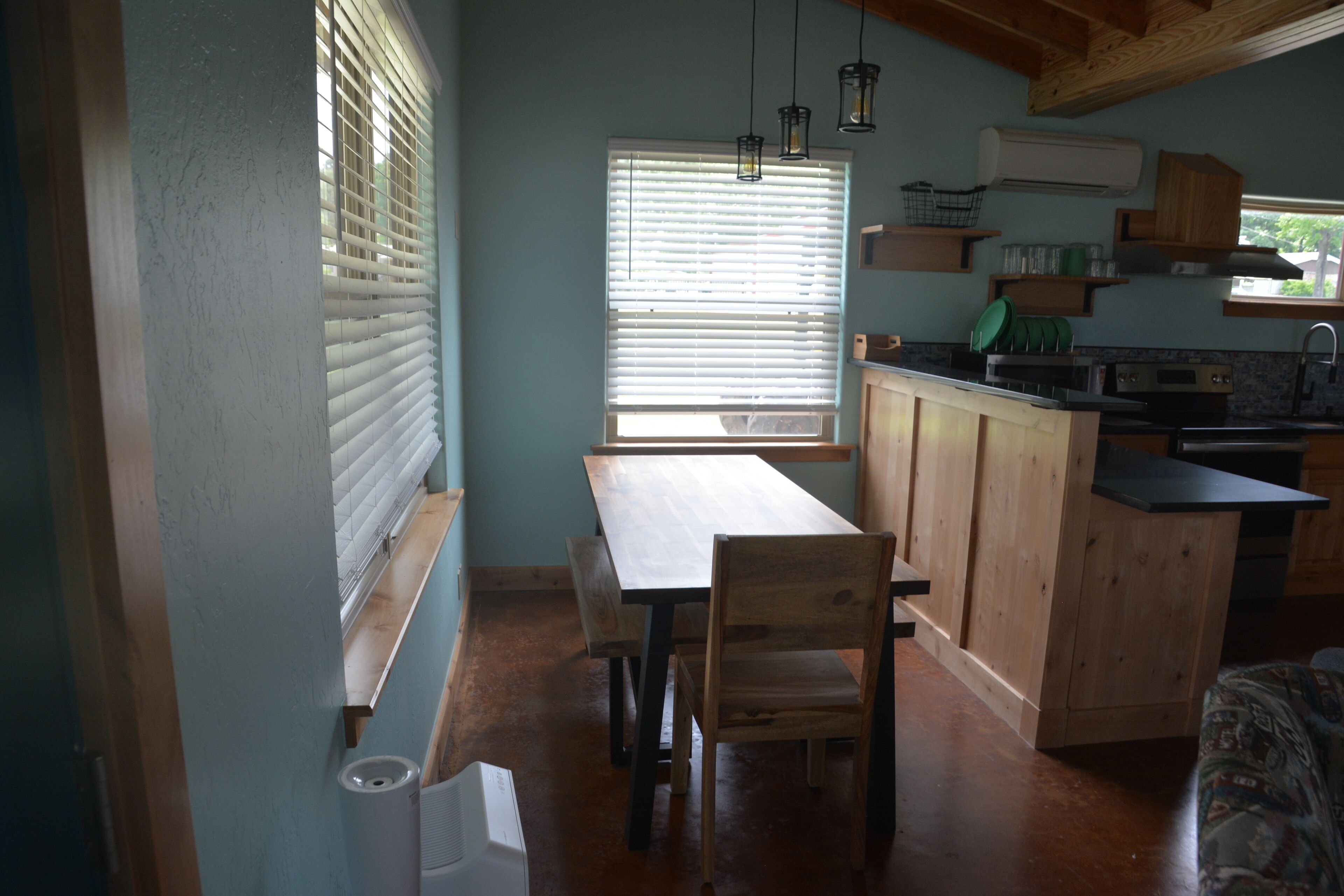 A kitchen with wooden cabinets, a dining table, and a window with blinds.