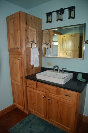 A bathroom with wooden cabinets, a white sink, and a mirror with three lights above it.