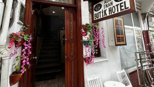The exterior of Ada Butik Hotel with a wooden entrance, a signboard, and outdoor seating. - Ada İnan Pansiyon (Adalar)