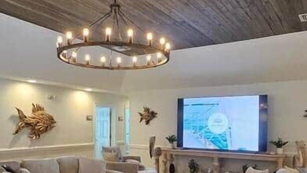 Una sala de estar con techo de madera, un sofá grande, una mesa de centro y un televisor.