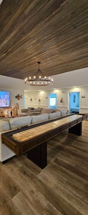 Un salon moderne avec un banc en bois, un lustre et un téléviseur.