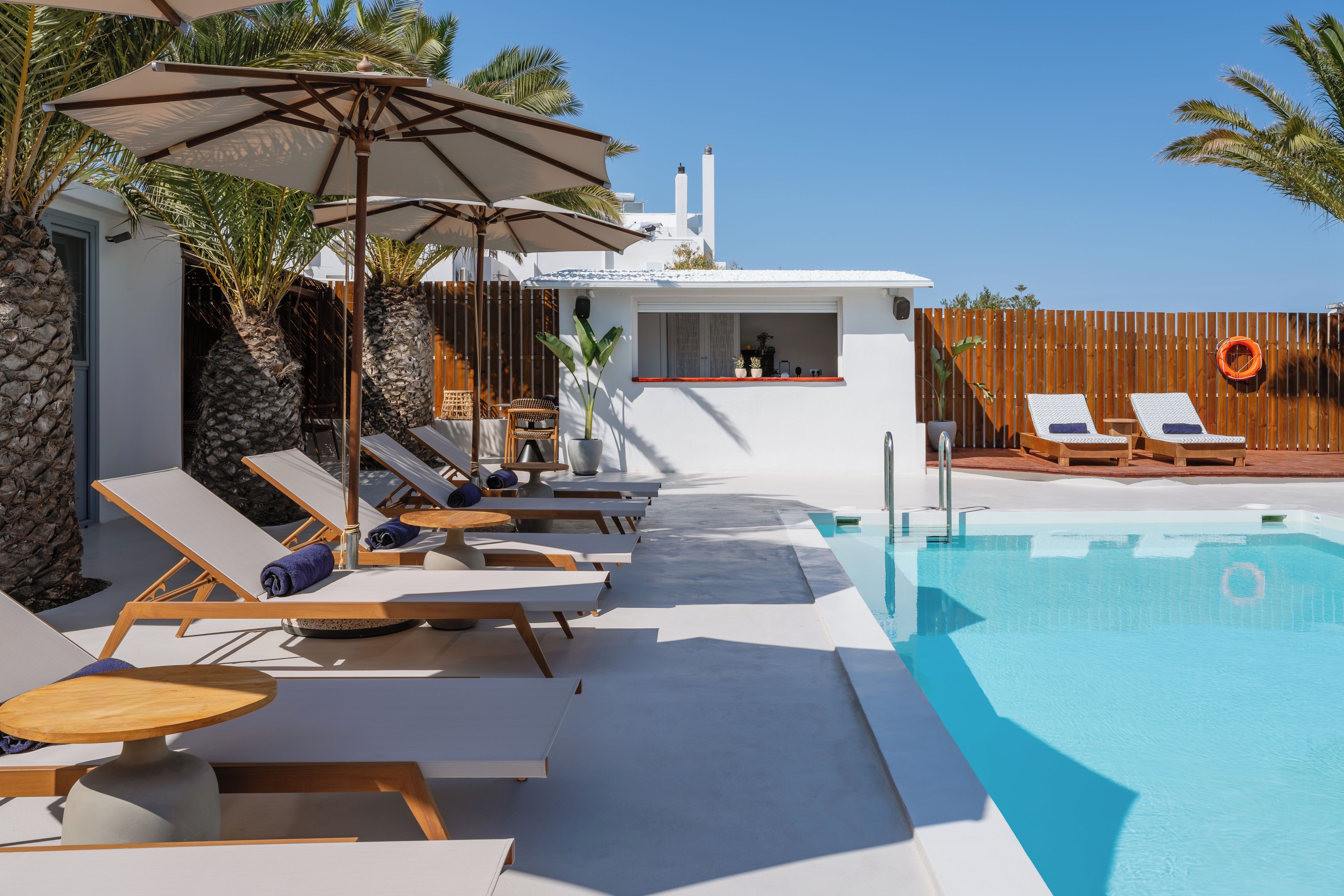 Ein Poolbereich mit Liegestühlen, Sonnenschirmen und einer Bar.