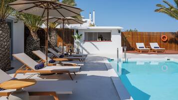 Ein Poolbereich mit Liegestühlen, Sonnenschirmen und einer Bar.