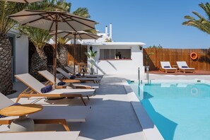 A poolside area with lounge chairs, umbrellas, and a bar.