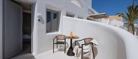 Un edificio blanco con un balcón, una mesa y sillas, y una puerta.