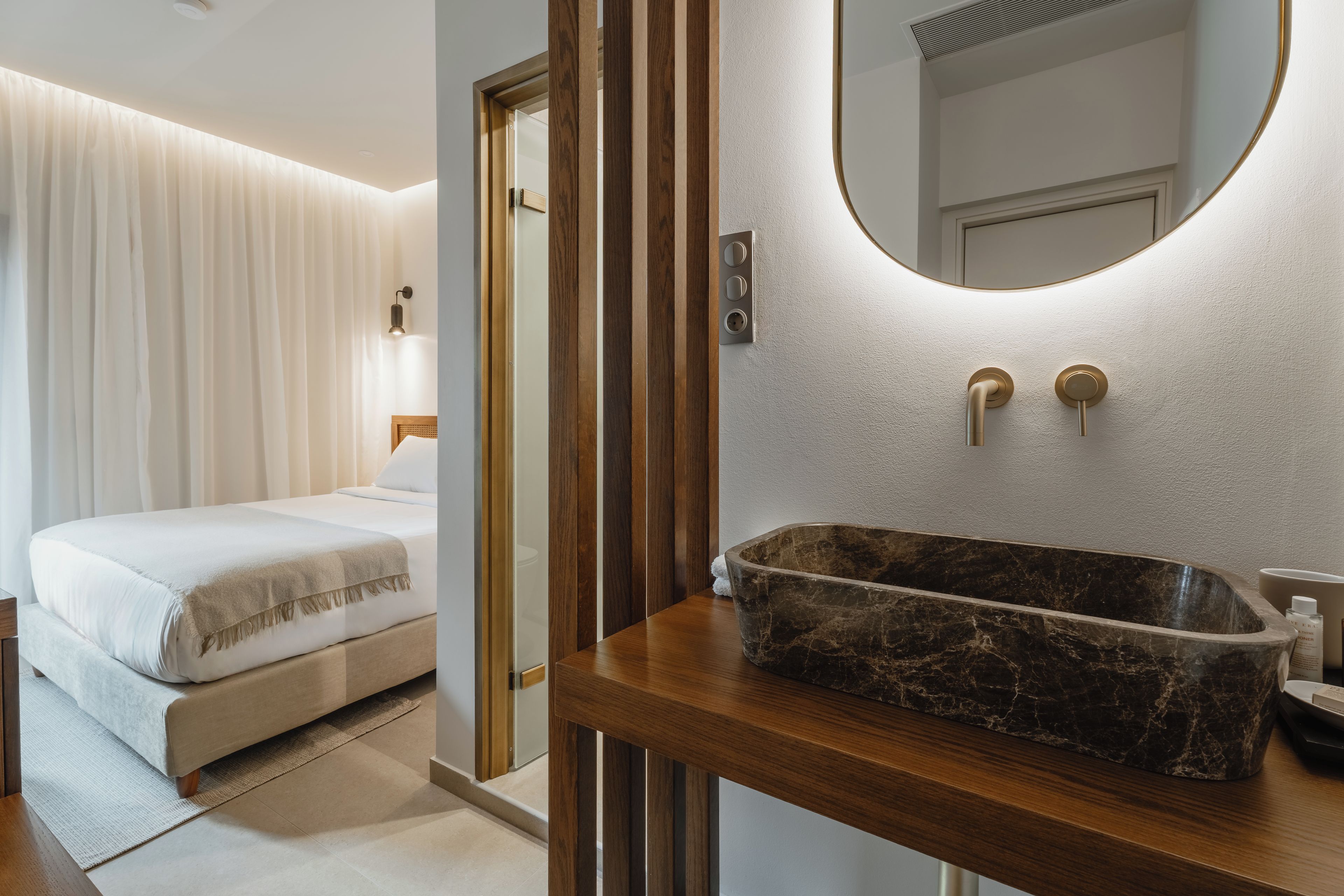 Ein Hotelzimmer mit einem Bett, einem Holzinlay und einem Marmorwaschbecken sowie einem Spiegel.