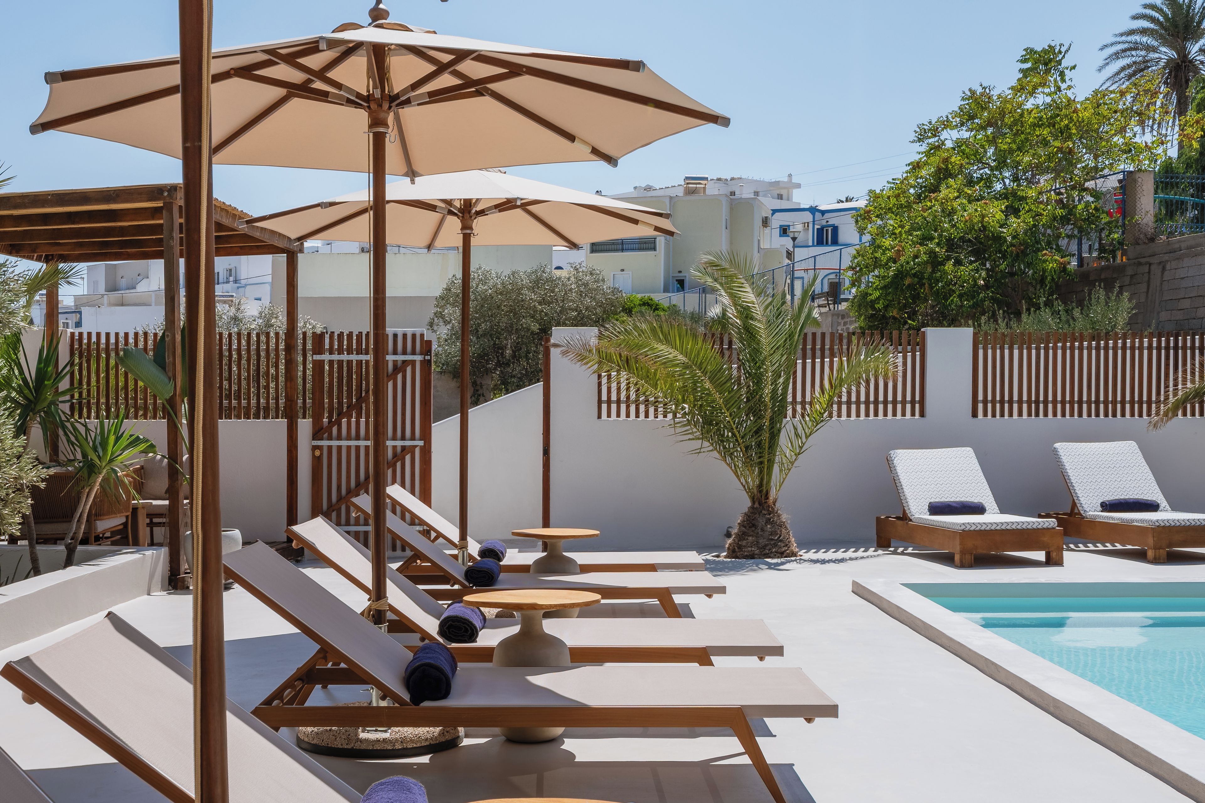 A poolside area with lounge chairs, umbrellas, and a small table.
