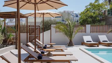 A poolside area with lounge chairs, umbrellas, and a small table.