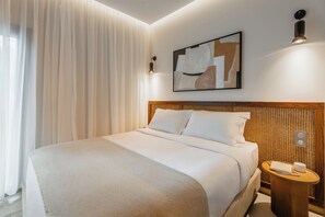 Een hotelkamer met een bed, nachtkastje, een wandlamp en een schilderij.