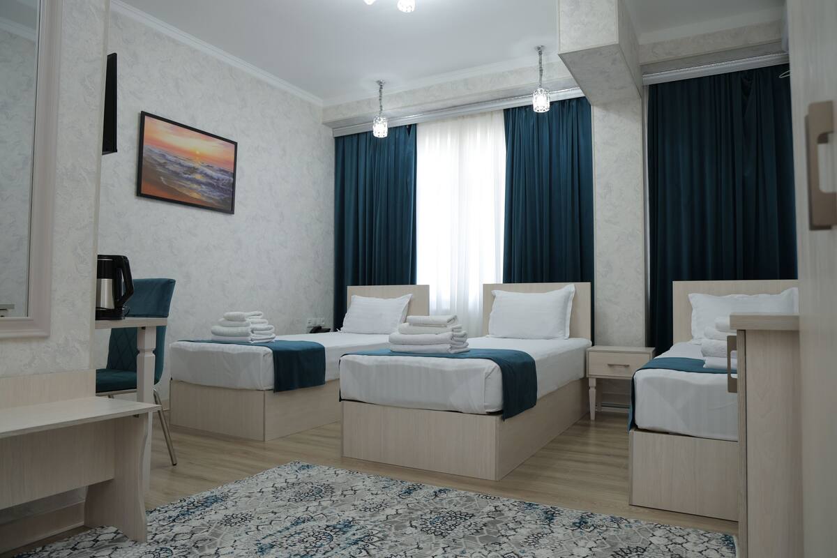 A hotel room with two beds, a desk, a chair, a coffee machine, and a painting on the wall.