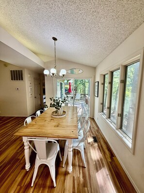 A dining area with a wooden table, white chairs, and a ceiling light fixture.