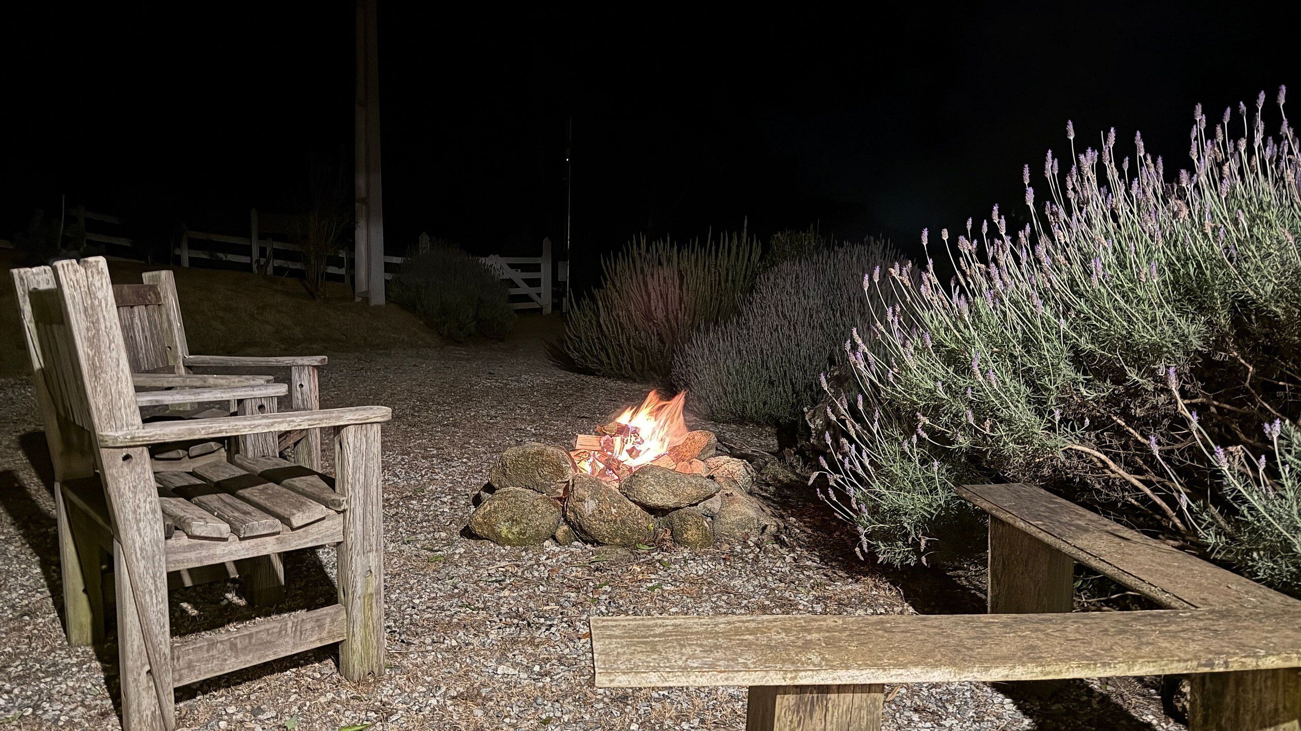 Un banco de madera y un pozo de fuego en un jardín por la noche.