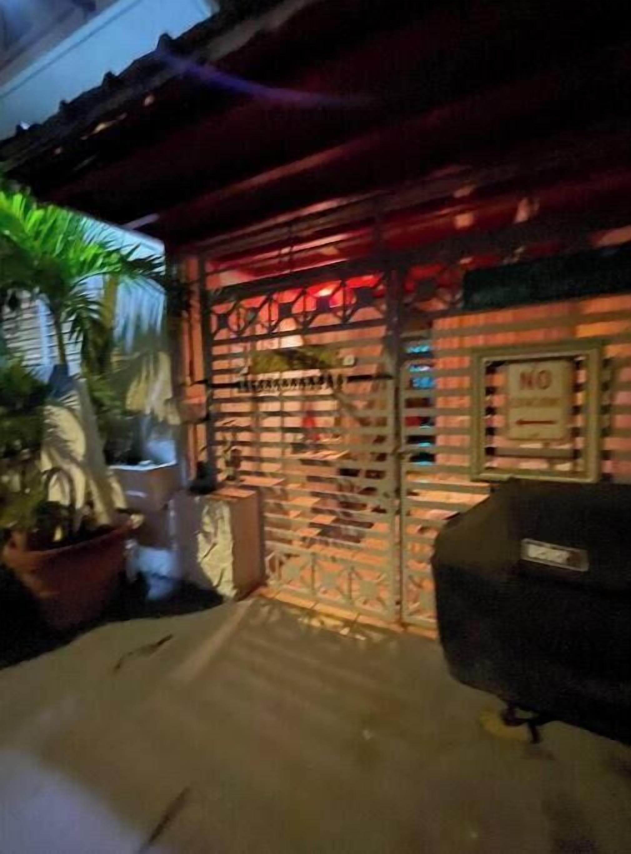 Un bâtiment avec un portail en métal et un panneau indiquant « INTERDIT », un pot de fleurs et un barbecue.