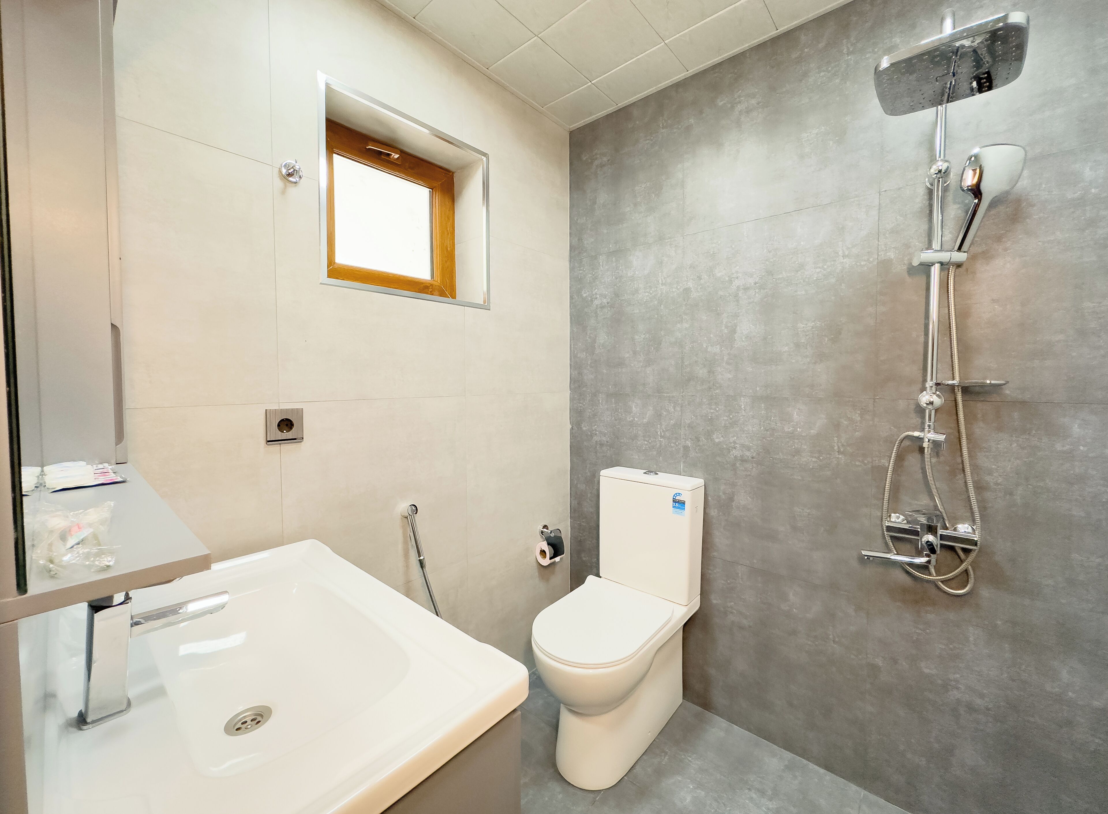 A modern bathroom with a white bathtub, a toilet, and a shower unit.