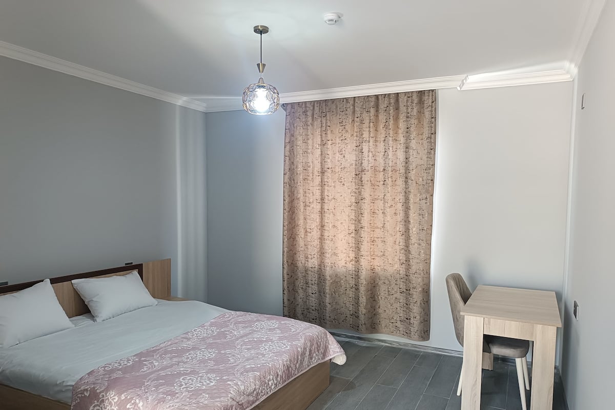 Een slaapkamer met een bed, een bureau en een stoel.
