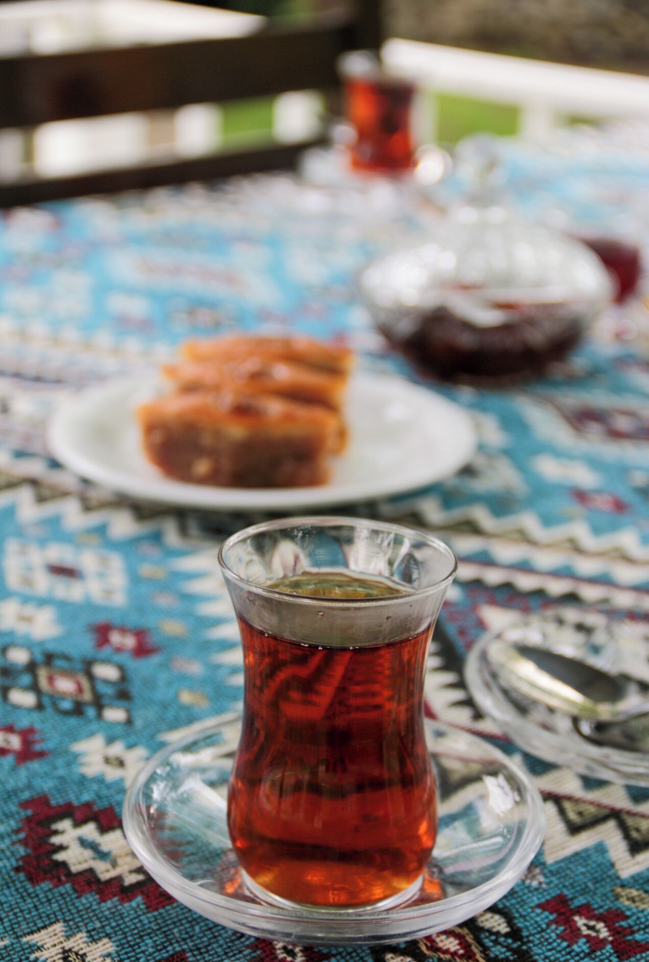 A table with a glass of tea, a plate with food, and a teapot.
