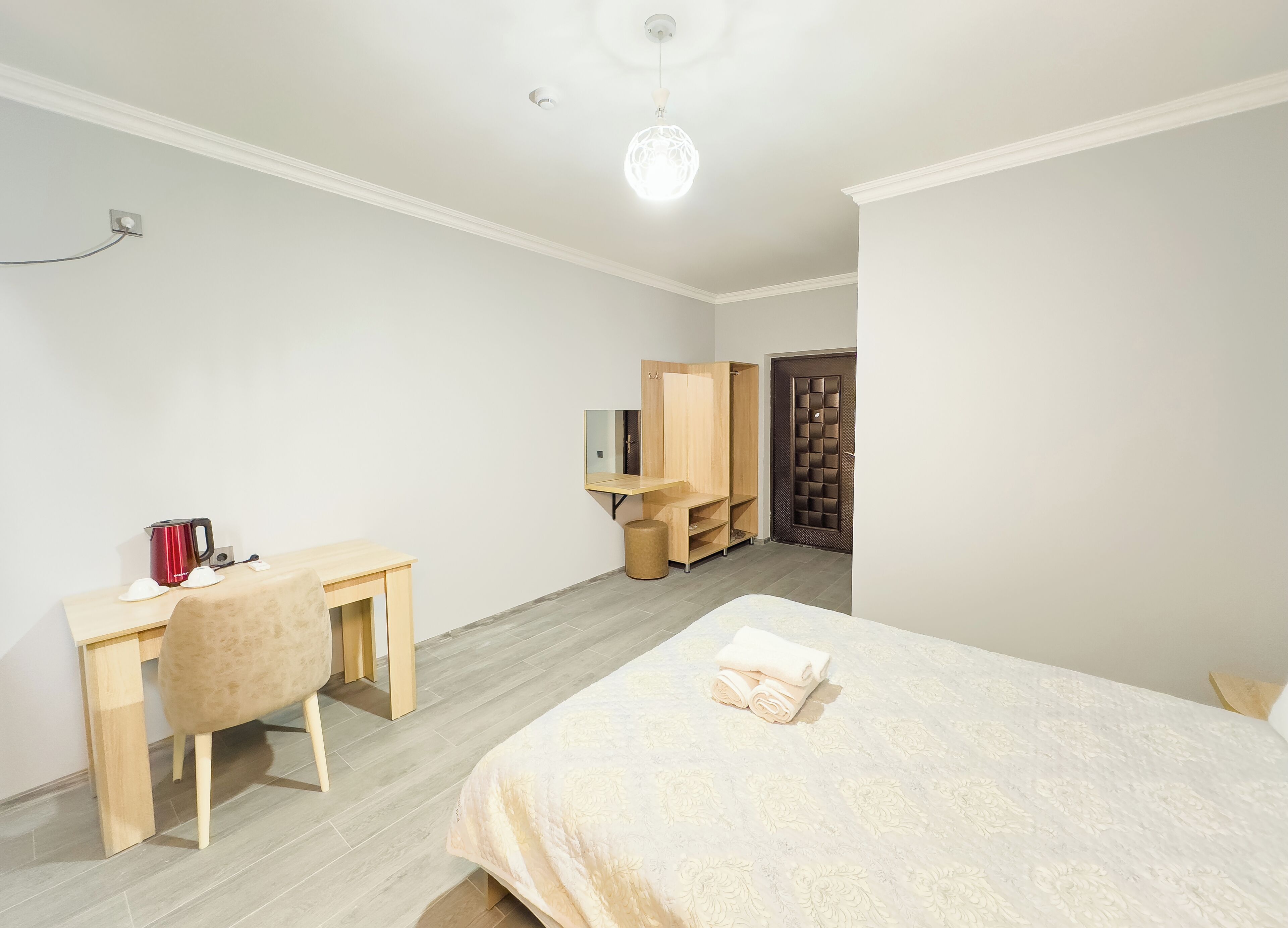 Une chambre à coucher avec un lit, un bureau, une chaise, une armoire et une porte.