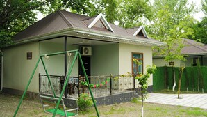 A house with a porch, a swing set, and a small garden. - River Garden Hotel Gabala (Gabala)