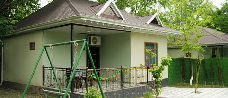 A house with a porch, a swing set, and a small garden.