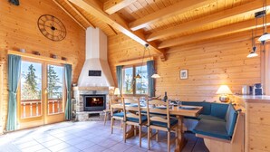A cozy cabin interior with a fireplace, wooden dining table, and seating area.
