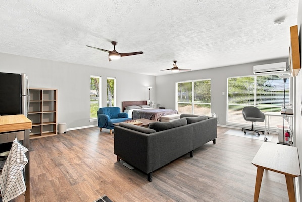 A spacious living area with a large sofa, a dining table, and a kitchen area with a refrigerator.