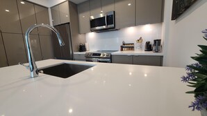 A modern kitchen with a stainless steel sink, a built-in oven, and a microwave above the stove.