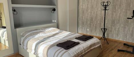 Un dormitorio moderno con una cama, suelo de madera, un armario y una lámpara de pie.