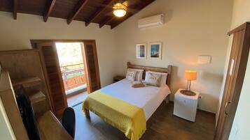 Un dormitorio con cama, mesita de noche, lámpara, ventilador de techo y ventana con contraventanas.