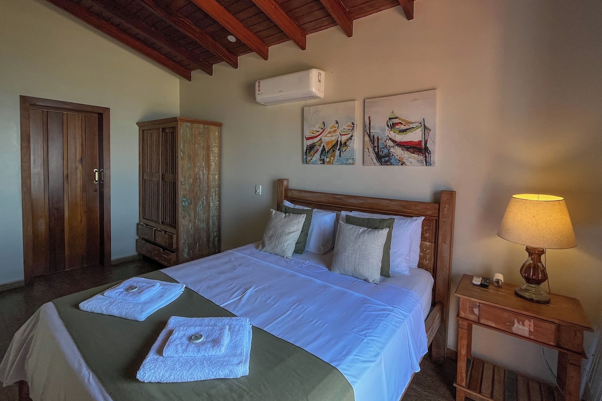 Un dormitorio con una cama de madera, una mesita de noche, una lámpara y cuadros en la pared.