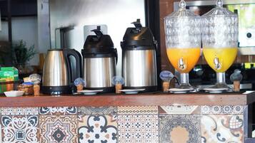 Uma bancada de cozinha com máquinas de café, um jarro de café e dois dispensadores de suco de fruta.