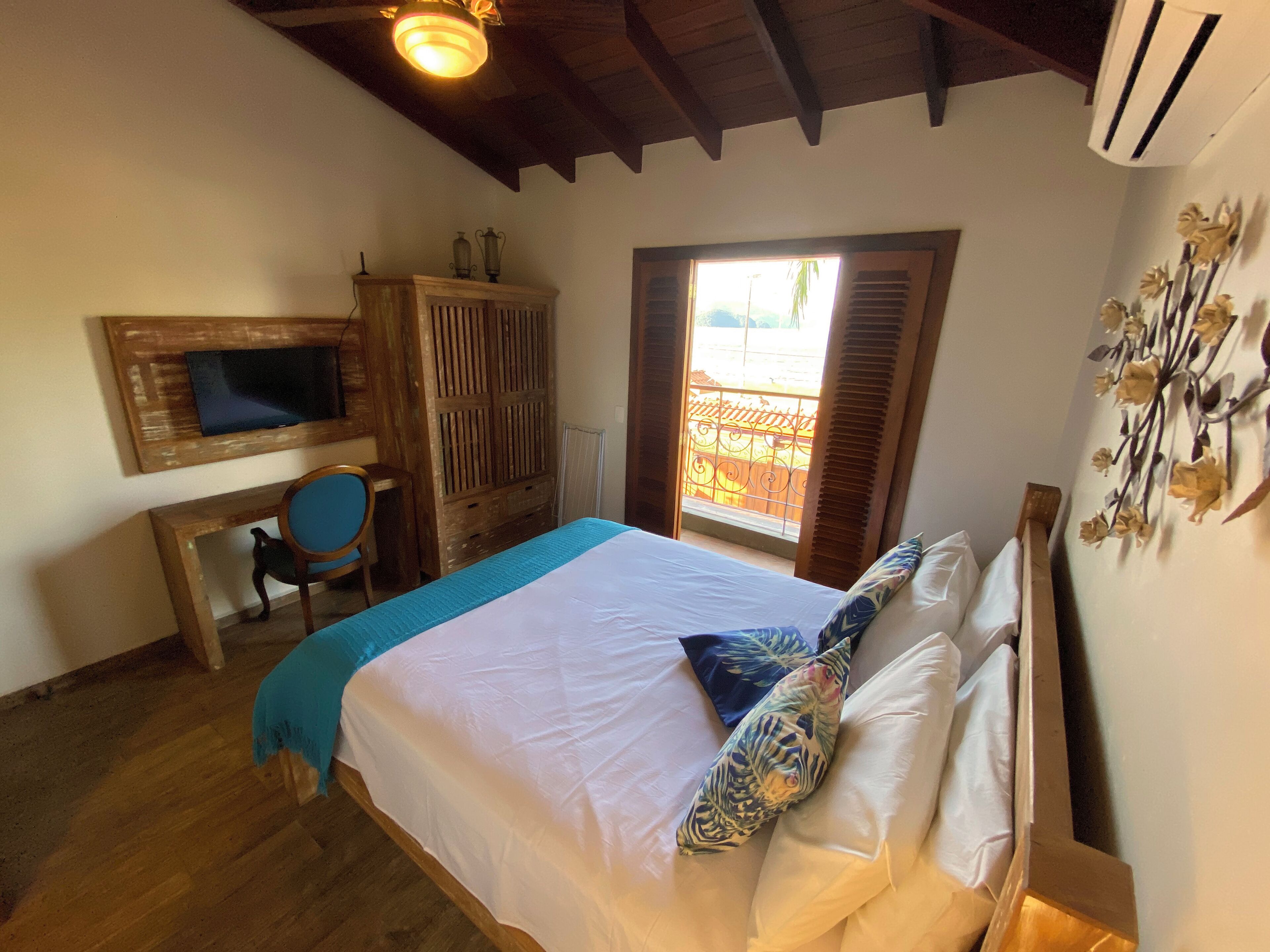 Un dormitorio con cama, escritorio, silla, armario y ventana con persianas.