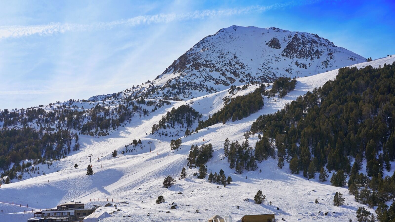 Paisaje nevado de montañas con una estación de esquí.