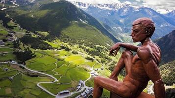 Una escultura de un hombre sentado que domina un valle con casas y carreteras.