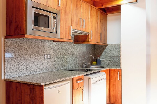 Una cucina con mobili in legno, un forno a microonde integrato, un lavello e una lavastoviglie.
