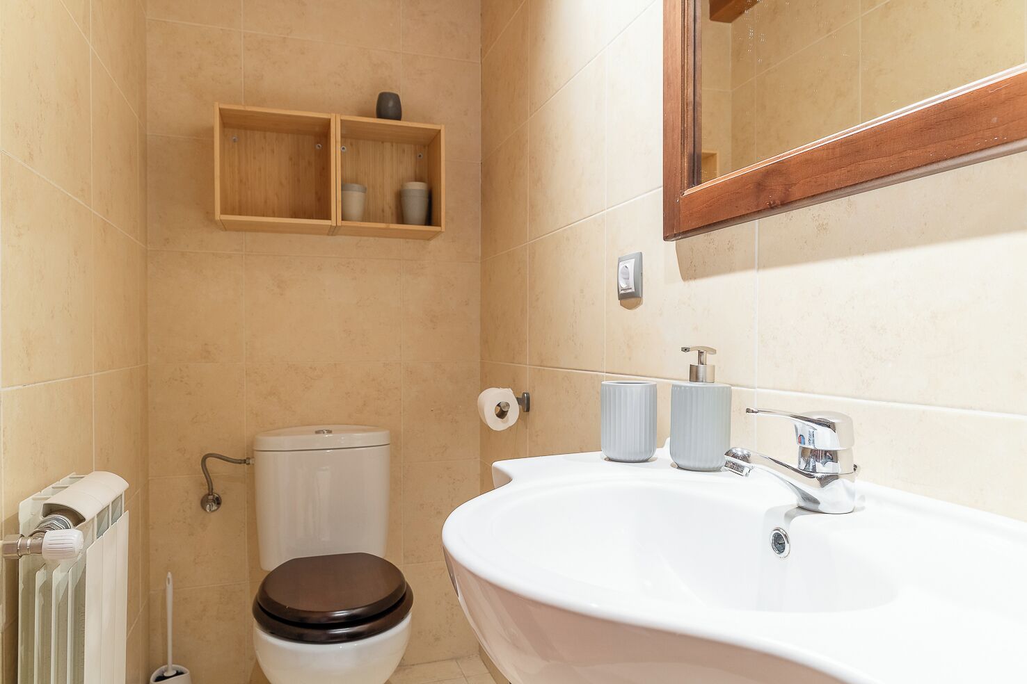 A bathroom with a white sink, a toilet, a mirror, and a shelf with toiletries.