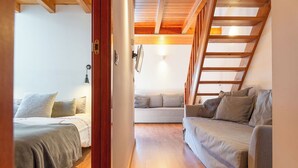 Une pièce confortable avec un lit, un canapé et un escalier menant à un étage supérieur.