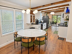 A modern kitchen with a central island, white cabinets, and a dining area with a round table and chairs.