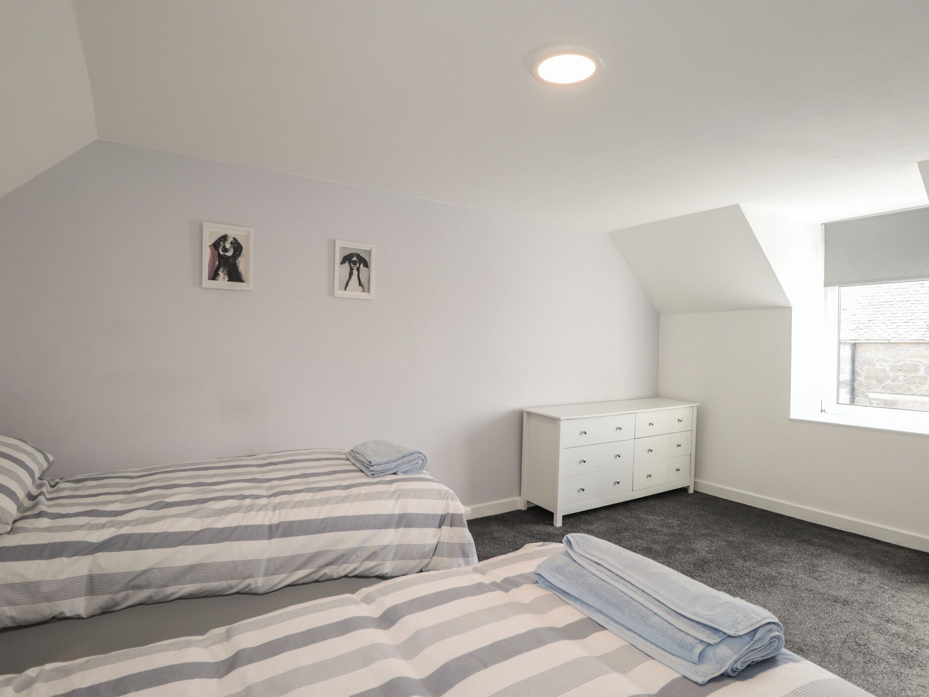 Un dormitorio con dos camas, un aparador blanco y una ventana.