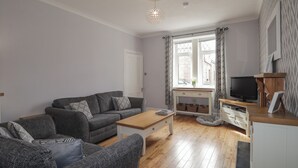 Un salon moderne avec un canapé gris, une table basse en bois et un meuble pour la télévision.