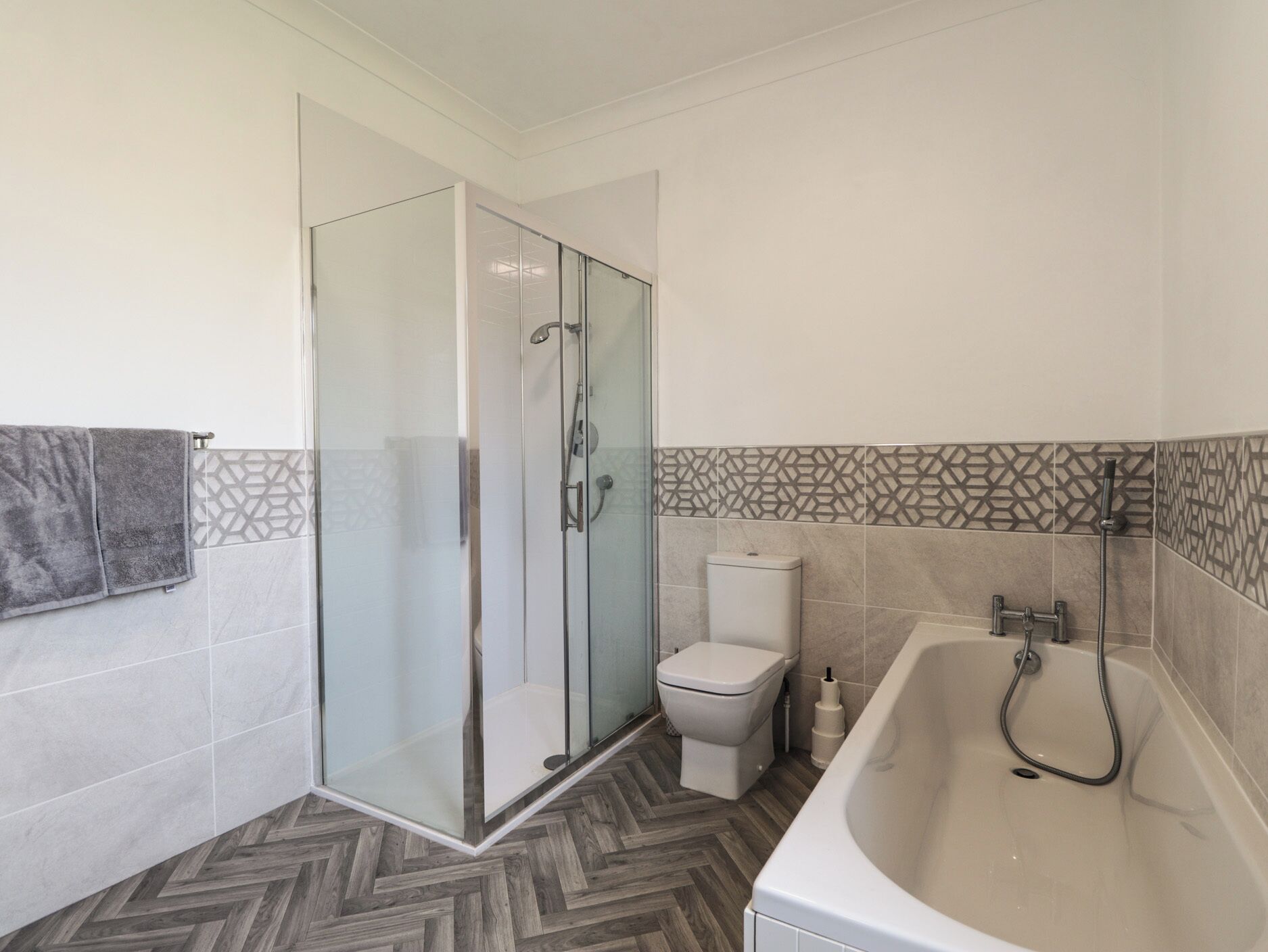 A modern bathroom with a glass-enclosed shower, a toilet, and a bathtub.