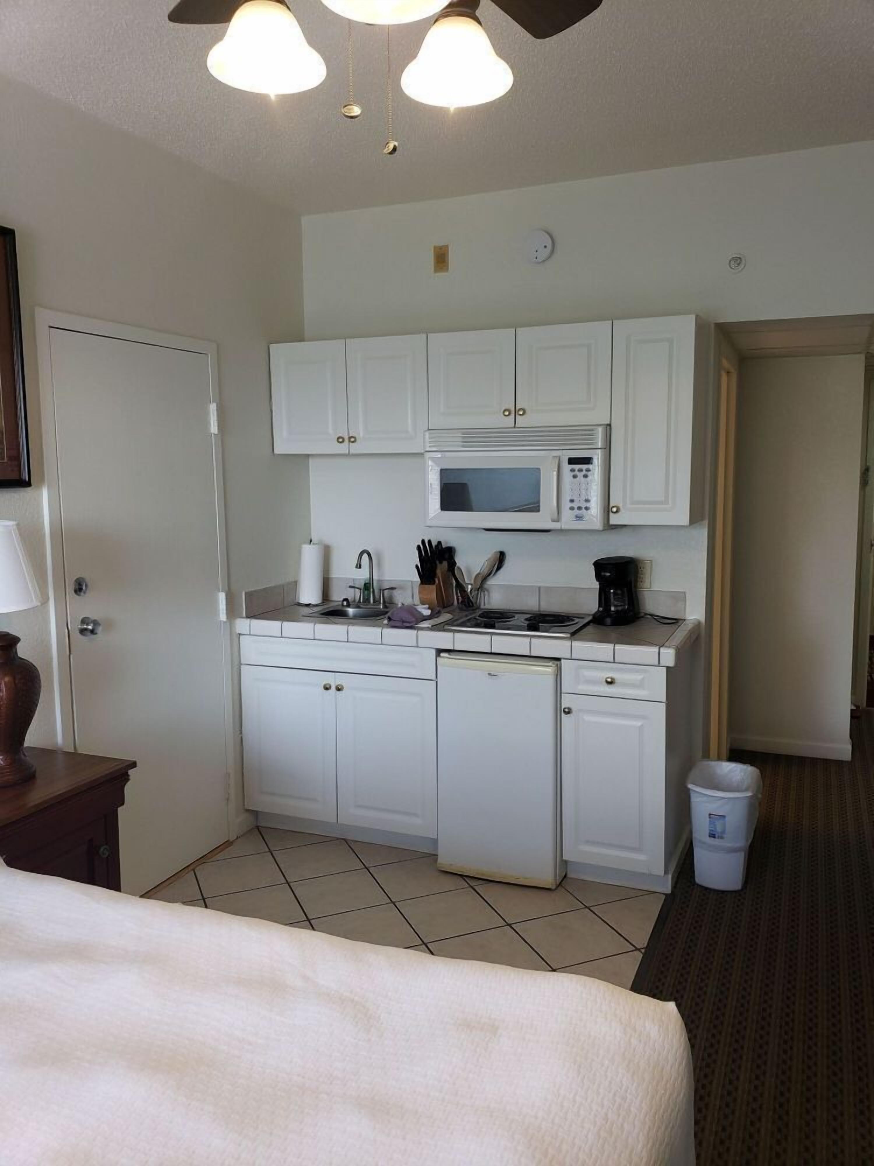 A compact kitchen with white cabinets, a microwave, a coffee maker, and a dishwasher.