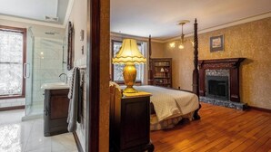 Un dormitorio amplio con una cama grande, una chimenea y una lámpara clásica.