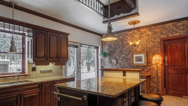 Una cocina con gabinetes de madera oscura, encimera de granito y una isla grande con taburetes.