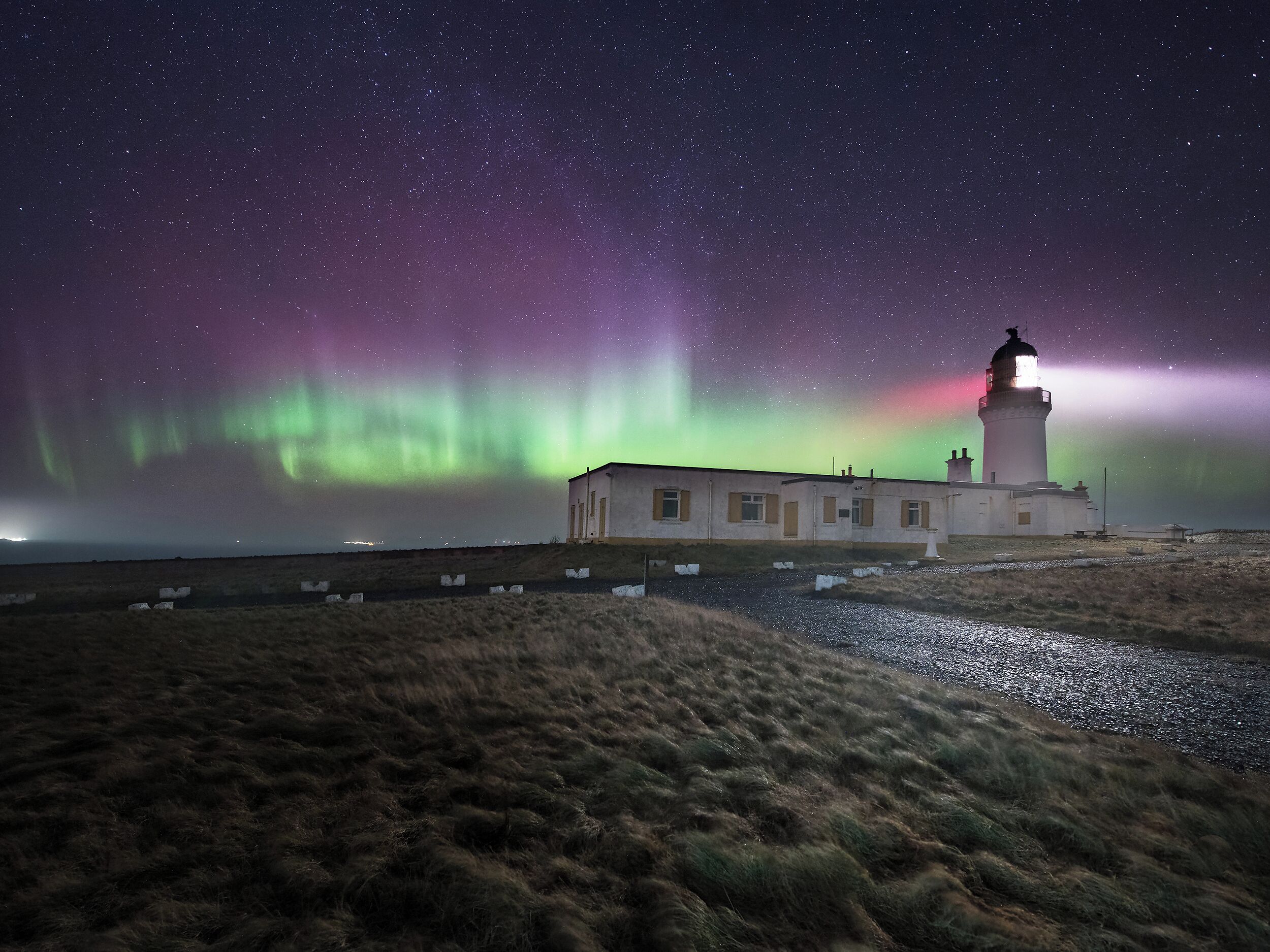 Un phare illuminé la nuit, offrant une vue dégagée sur le ciel et les étoiles.