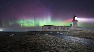 Un phare illuminé la nuit, offrant une vue dégagée sur le ciel et les étoiles.