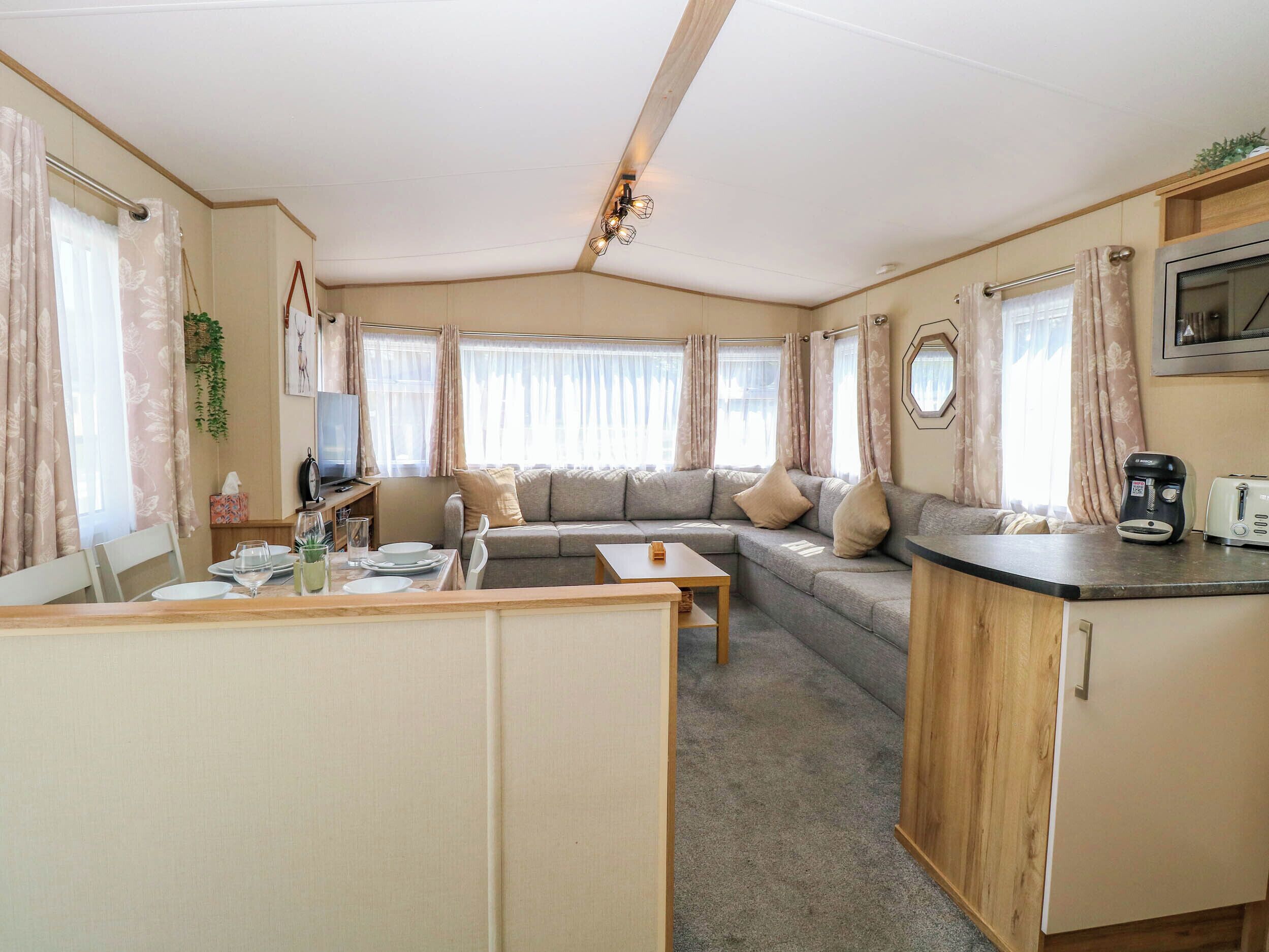 A compact living space with a sofa, dining table, kitchenette, and a television.