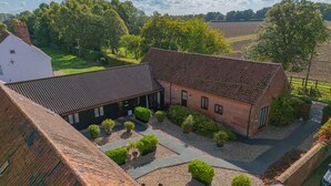 A courtyard with a brick building, potted plants, and a gravel path. - Willow (Dereham)