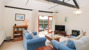 A living room with a sofa, a coffee table, a bookshelf, a television, and a fireplace. - Willow (Dereham)
