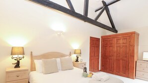 A bedroom with a wooden bed, two bedside tables with lamps, a nightstand, a wardrobe, and a dresser. - Willow (Dereham)