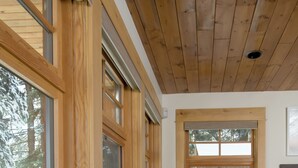 Un pasillo con paredes de madera y ventanas amplias, un banco y un suelo con diseño de piedra.